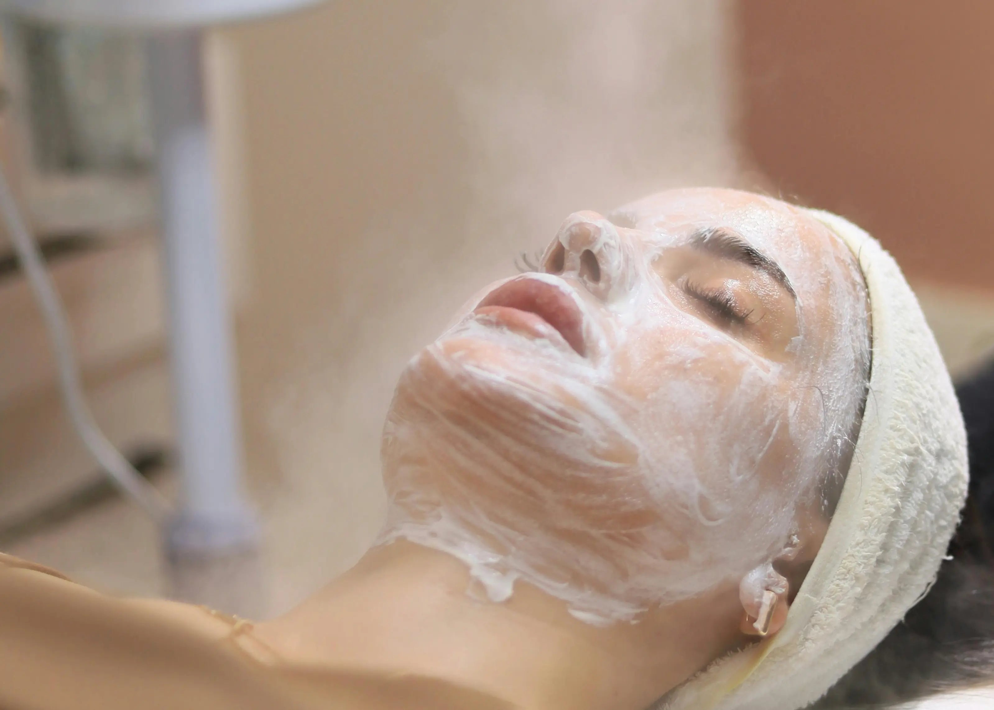 Person receiving a facial treatment with a towel on their head